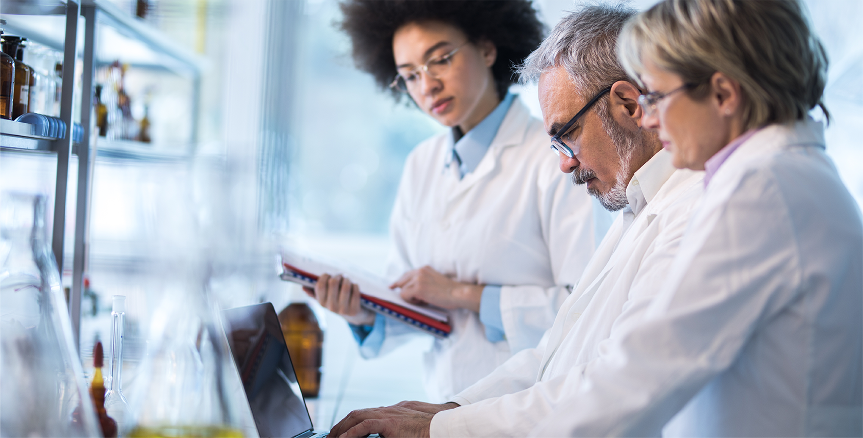 three medical practitioners collaborate around a computer